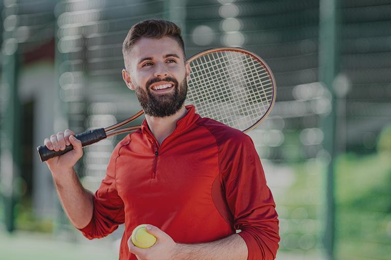 mężczyzna z rakietą tenisową w czerwonej koszuli